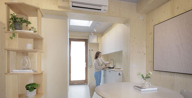 Tuuliturbiinitalon sisätila joka on paljolti vaaleaa puupintaa, vasemmalla koristeellinen hylly jossa kasveja, ja taka-alalla pieni keittiötila.