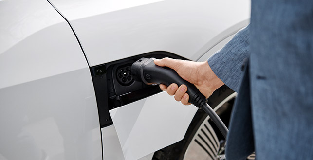 Kuvituskuva: mies lataa sähköautoa.