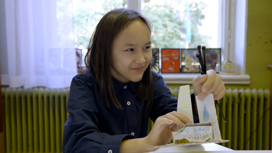 Lapsi pahvisen vetyautomallin kanssa