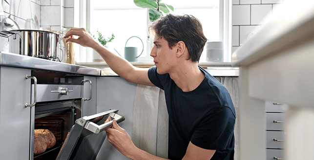 Mies keittiössä avaa tiskikonetta