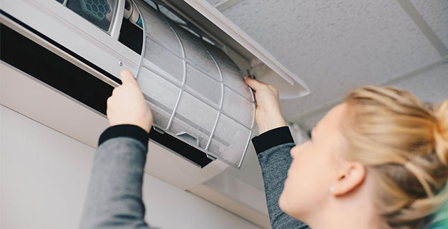 Nainen vaihtamassa ilmalämpöpumpun suodatinta