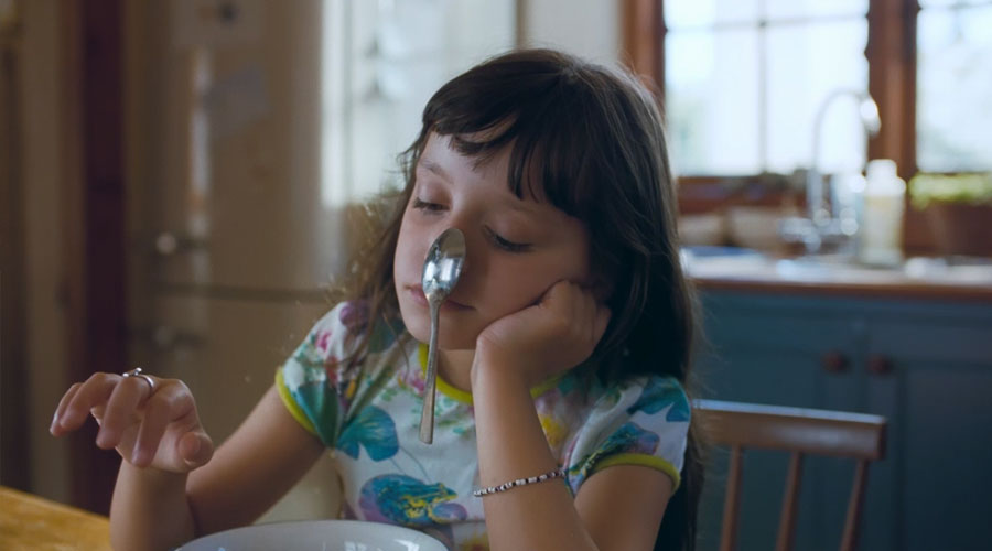 Pieni tyttö pöydän ääressä lusikan kanssa