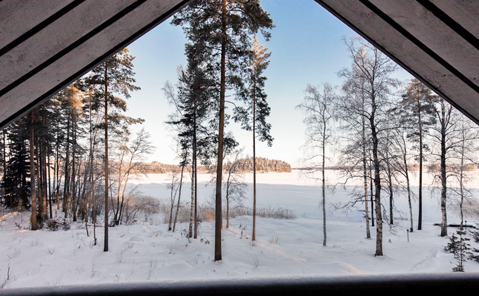 Mökin katon räystäät reunustavat kuvaa mökin edustan talvisesta maisemasta