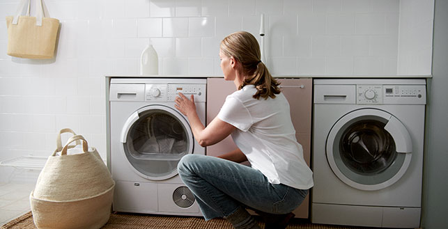 Nainen säätämässä pyykkikonetta