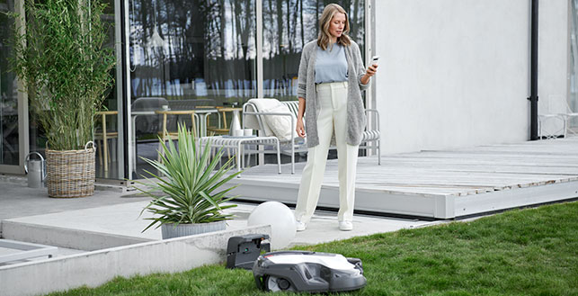 Nainen pihalla katsoo kännykkää