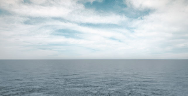 Kuva: merimaisema, jossa näkyy pilvinen taivas ja tyyni merenpinta