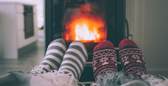 Kahdet jalkaparit pehmeissä sukissa takan edustalla