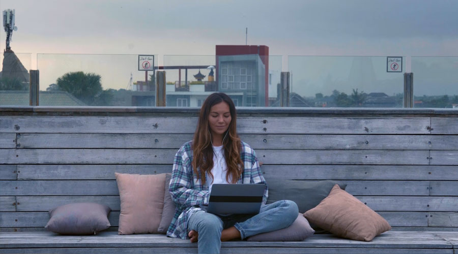 Nainen iltahämärällä kattoterassilla selaamassa tablettia