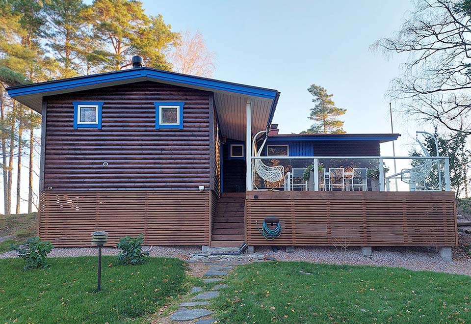 Kuva mökin ulkopuolelta, jossa näkyy koko julkisivu