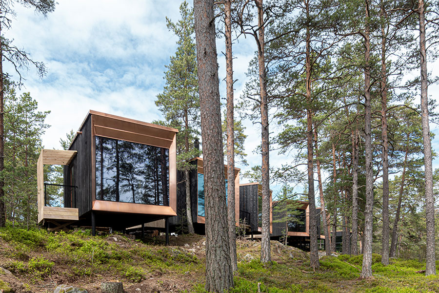 Kuutionmallinen, puusta rakennettu Barön hotelli ulkoapäin, ympärillä mäntymetsää