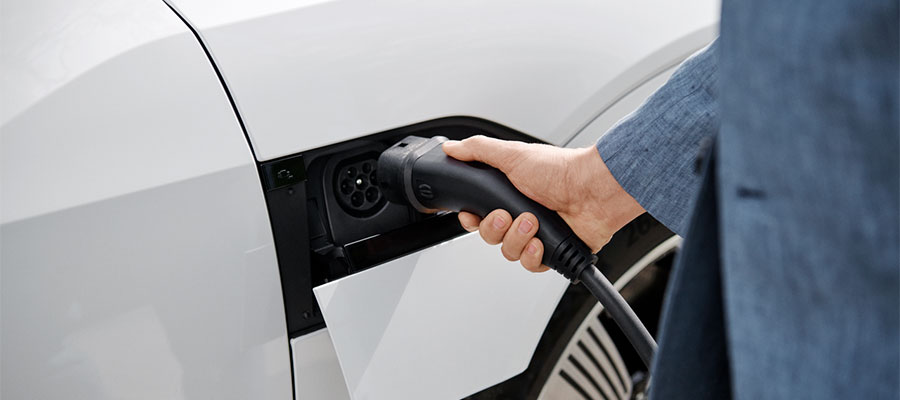 Henkilö lataa sähköautoa