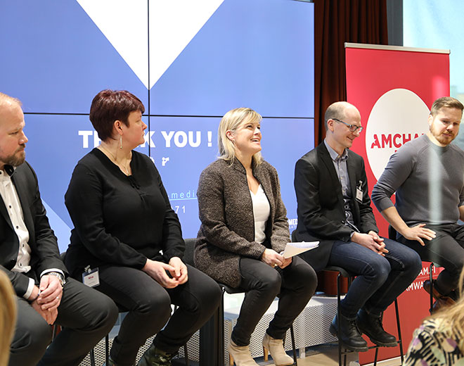 Viisi keskustelijaa istumassa lavalla ja puhumassa Amchamin tilaisuudessa