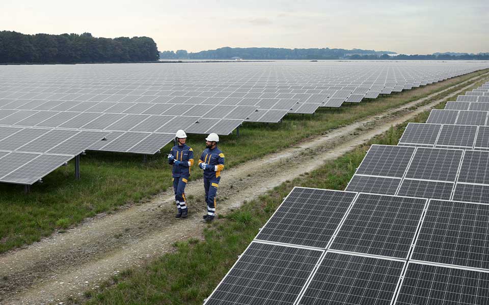 Työntekijät kävelevät aurinkopuistossa ja keskustelevat keskenään