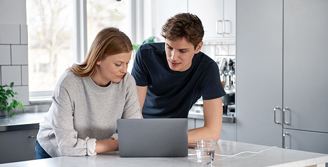 Nainen ja mies keittiössä läppärin ääressä