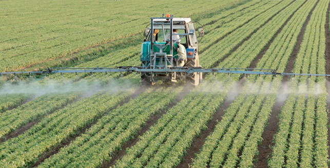 Vihreää peltoa jota sumutetaan traktorilla