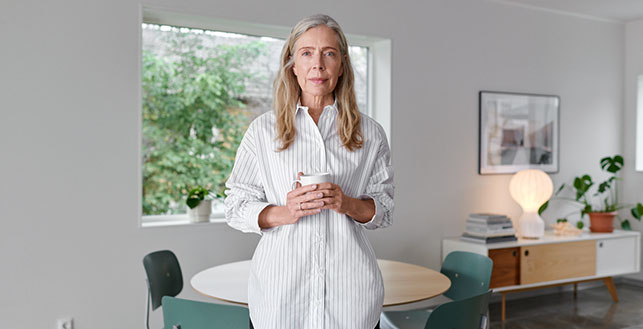 Vanhempi nainen kotona kahvikuppi kädessään