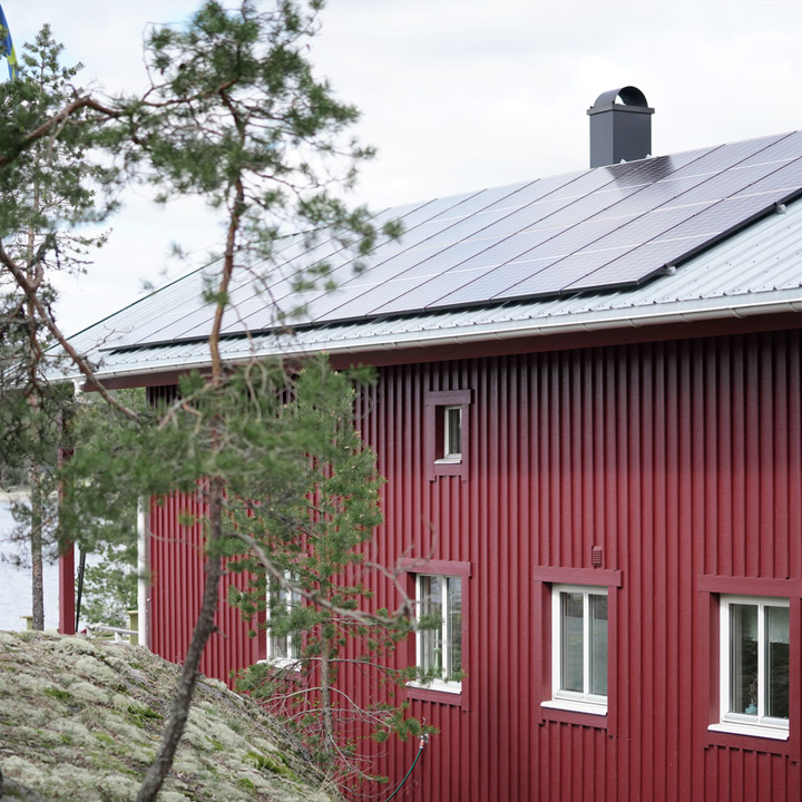 Aurinkopaneeleja punaisen mökin katolla