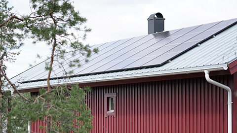 Solceller på taket av ett rött hus.