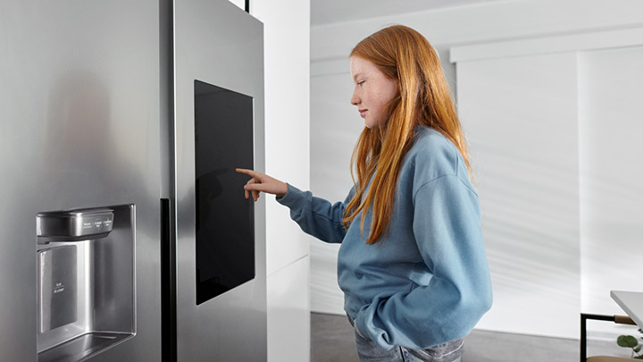 Tyttö muuttaa kodinkoneen säätöjä kosketustaulusta