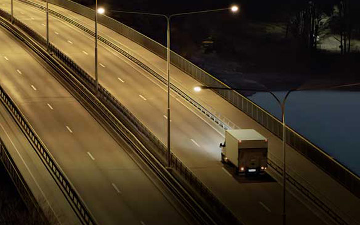 Öinen valaistu autotie jota pitkin ajaa muuttoauto