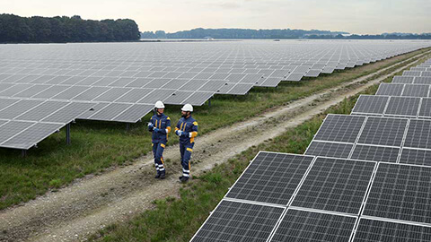 Kaksi ihmistä suuren aurinkovoimalan keskellä.