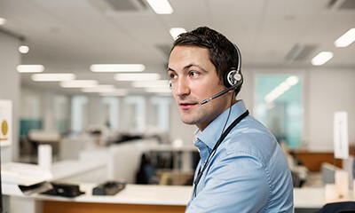 Mies kuulokkeet päässä avokonttorissa