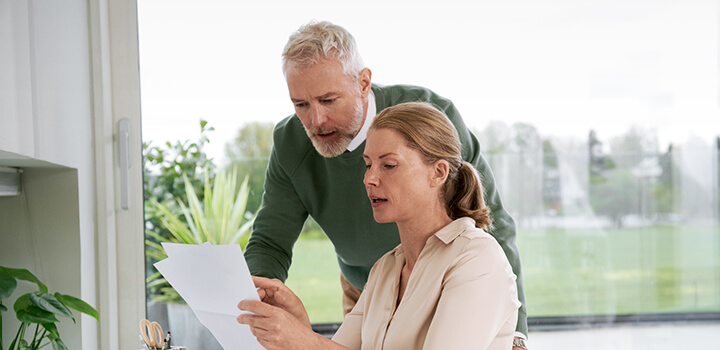 Nainen ja mies kotitoimistolla tutkimassa papereita.