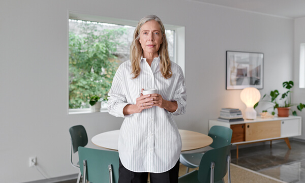 Nainen, joka pitää kuumaa juomaa olohuoneessa