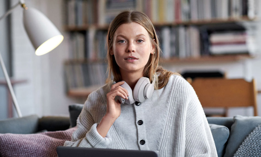 Nainen harmaassa villaneuleessa katsoo kameraan