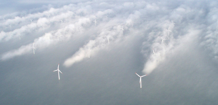 Kuva kaukaa ylhäältä jossa näkyy tuulipuisto merellä