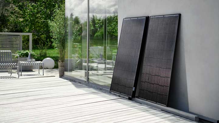 Kaksi aurinkopaneelia nojaa talon seinää vasten