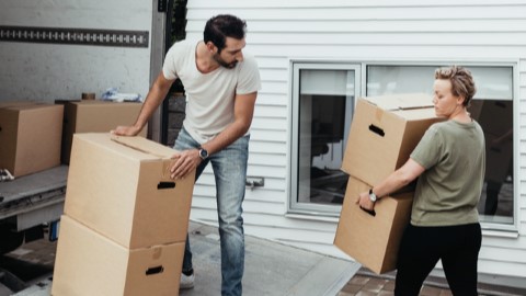 Pariskunta kantamassa muuttolaatikoita