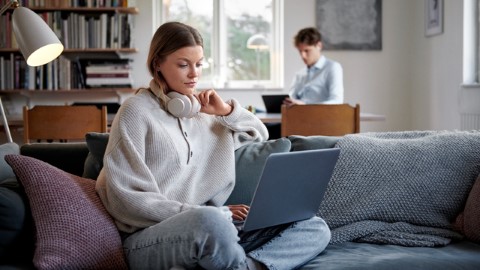 Nuoret aikuiset tietokoneiden kanssa olohuoneessa