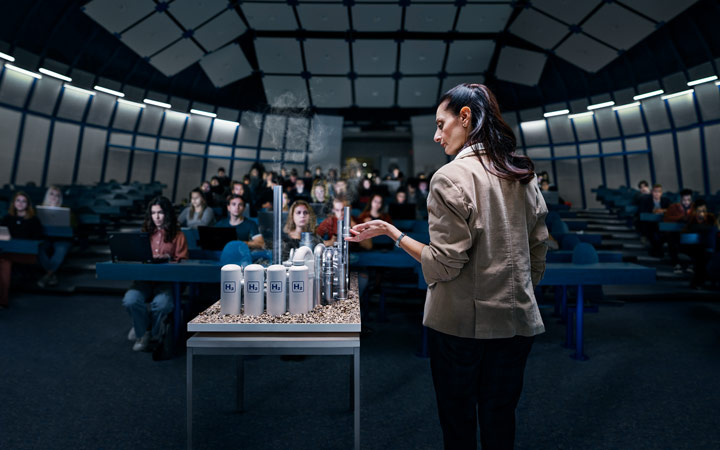 Nainen esittelee yleisölle tuotannon pienoismallia