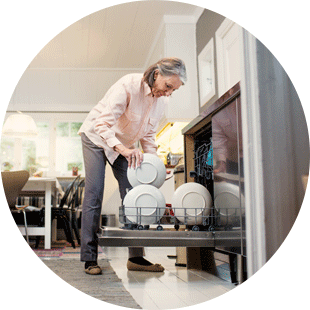 Nainen täyttämässä tiskikonetta