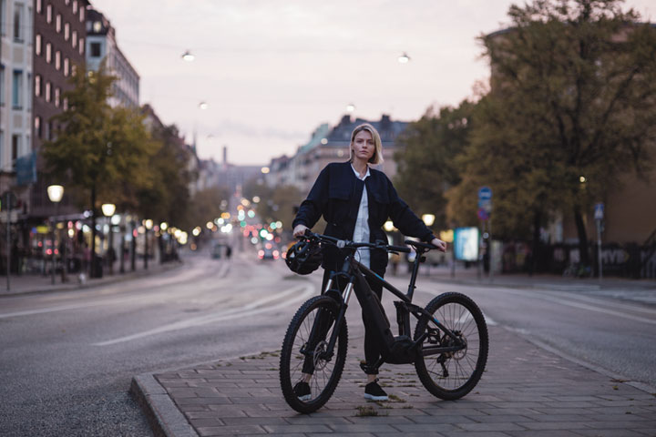 Nainen illansuussa kaupungissa polkupyörän kanssa